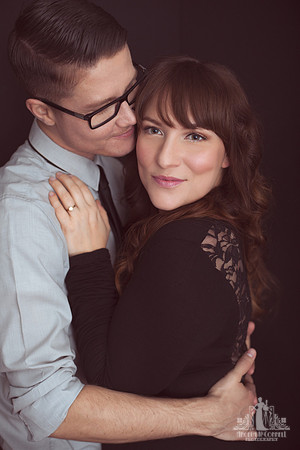 Contemporary studio portrait of a couple cuddling while looking at the camera by Vancouver portrait photographer Angela McConnell