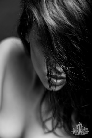 Black and white portrait of a young woman with hair obscuring her face