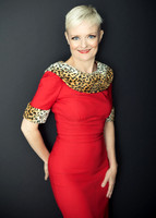 Portrait of an older woman in a red dress with leopard trim and short blonde hair smiling at the camera