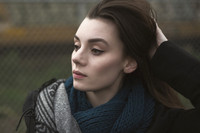Outdoor portrait of a young woman in winter clothes brushing her fingers through her hair