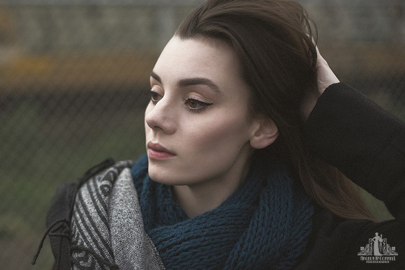Outdoor portrait of a young woman in winter clothes brushing her fingers through her hair
