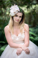 Natural light portrait of a young woman in the forest with flowers in her hair looking at the camera