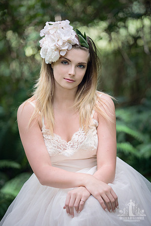 Natural light portrait of a young woman in the forest with flowers in her hair looking at the camera