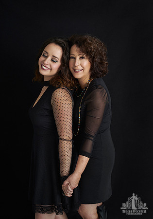 Contemporary portrait of a middle aged woman and her adult daughter holding hands and smiling by Vancouver portrait photographer Angela McConnell