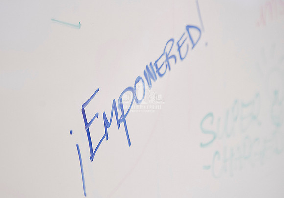 The word Empowered written on a white board in blue ink during a workshop