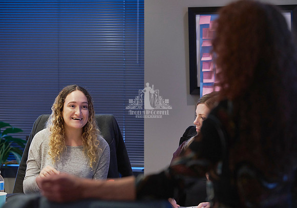Young woman with curly blond hair talking with the presenter facing her at a workshop