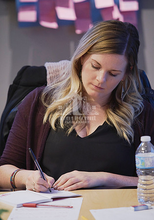 A woman writes in a notebook during a workshop