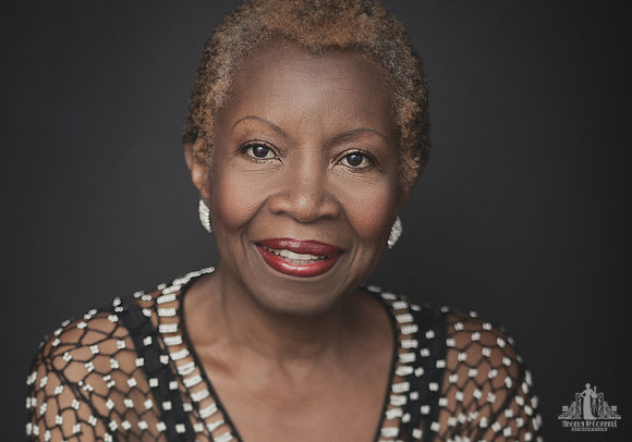 Contemporary studio portrait of an older black woman with natural hair and red lipstick smiling directly at the camera by Vancouver portrait photographer Angela McConnell