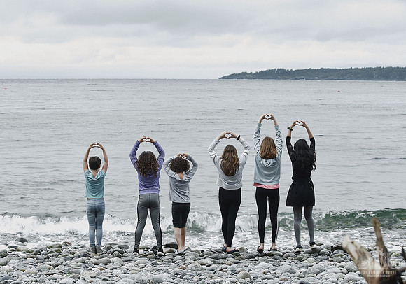 Girls play by the water on a pebble beach at Halfmoon Haven in Sechelt BC
