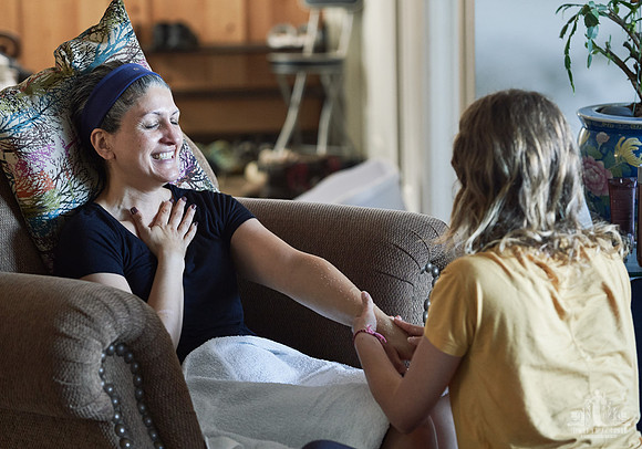 A woman smiles while receiving a hand massage  at a womens' retreat at Halfmoon Haven on the Sunshine Coast, BC by Vancouver workshop and retreat photographer Angela McConnell