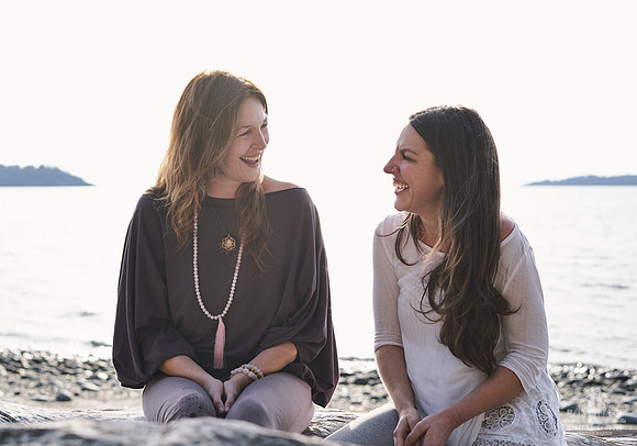 Portrait of two women smiling at each other on the beach at a womens' retreat at Halfmoon Haven on the Sunshine Coast, BC by Vancouver workshop and retreat photographer Angela McConnell