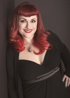 Portrait of a curvy young woman with red hair and red lipstick smiling at the camera