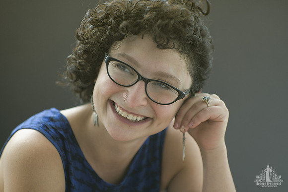 Natural light portrait of a young woman with curly hair smiling