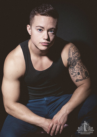 Portrait of a muscular young man with tattoos looking at the camera